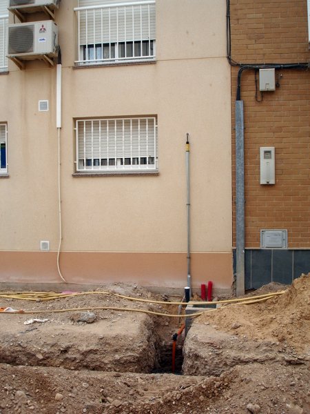 Zanja abierta junto a un edificio para una acometida de servicios