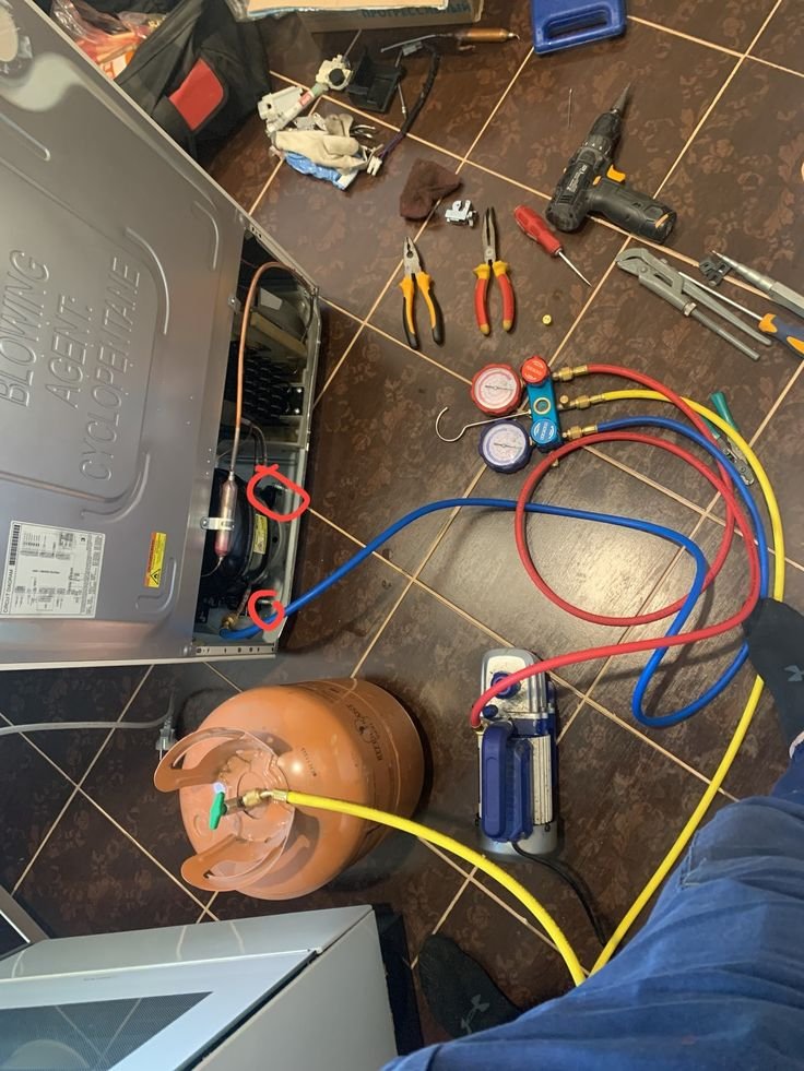 Manómetros y botella de gas refrigerante durante una carga de equipo