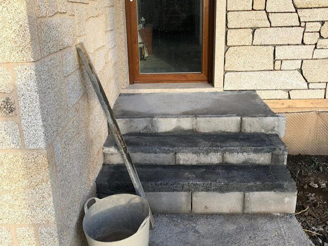Escalera exterior de obra nueva junto a la entrada de una vivienda