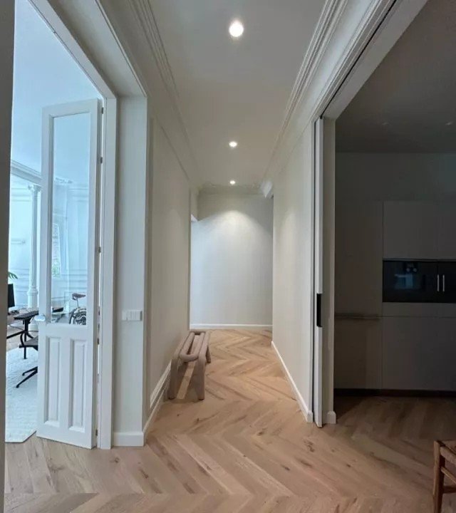 Pasillo reformado con suelo de madera en espiga y puertas correderas