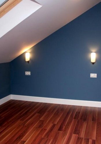 Habitación pintada en azul con apliques de pared y suelo de madera
