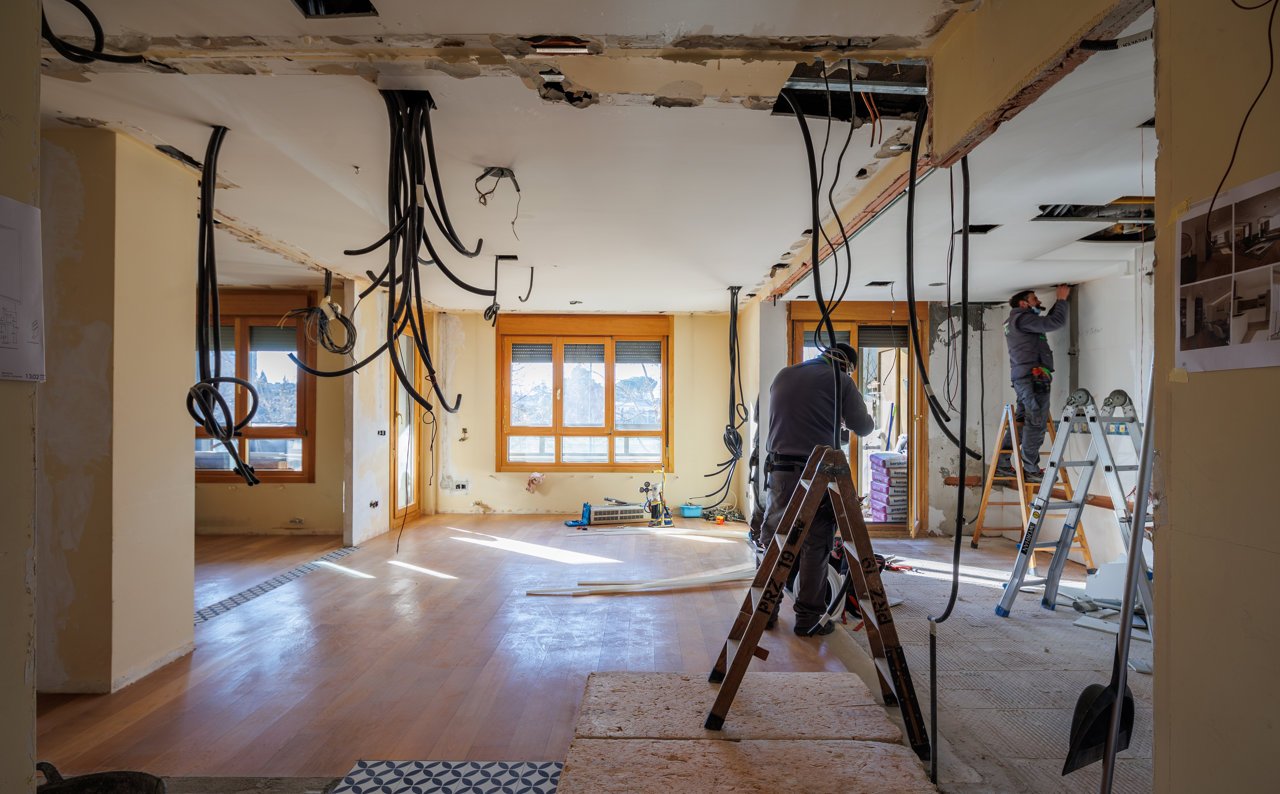Reforma integral de vivienda en curso con instalaciones vistas y operarios trabajando